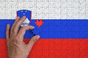 Slovenia flag  is depicted on a puzzle, which the man's hand completes to fold photo