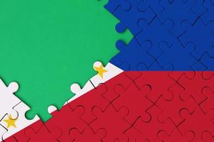 Philippines flag  is depicted on a completed jigsaw puzzle with free green copy space on the left side photo