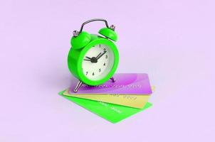 Small alarm clock lies on colored credit cards photo