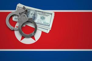North Korea flag  with handcuffs and a bundle of dollars. The concept of breaking the law and thieves crimes photo