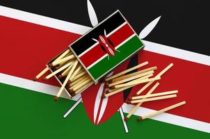 Kenya flag  is shown on an open matchbox, from which several matches fall and lies on a large flag photo