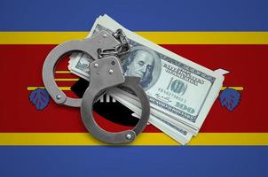 Swaziland flag  with handcuffs and a bundle of dollars. Currency corruption in the country. Financial crimes photo