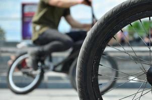 A BMX bike wheel against the backdrop of a blurred street with cycling riders. Extreme Sports Concept photo