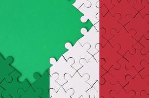 Italy flag  is depicted on a completed jigsaw puzzle with free green copy space on the left side photo