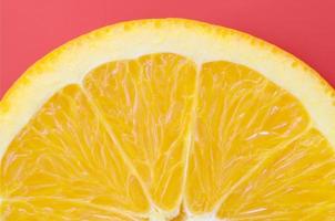 Top view of a one orange fruit slice on bright background in red color. A saturated citrus texture image photo