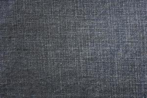 Detailed abstract texture of dark blue denim cloth. Background image of old used denim trousers fabric photo