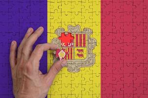 la bandera de andorra está representada en un rompecabezas, que la mano del hombre completa para doblar foto