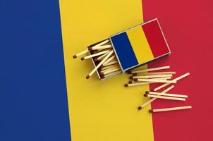 Romania flag  is shown on an open matchbox, from which several matches fall and lies on a large flag photo