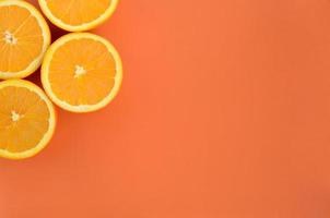 Top view of a several orange fruit slices on bright background in orange color. A saturated citrus texture image photo