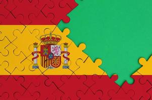 Spain flag  is depicted on a completed jigsaw puzzle with free green copy space on the right side photo