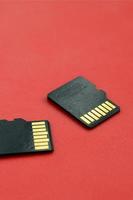 dos pequeñas tarjetas de memoria micro sd se encuentran sobre un fondo rojo. un pequeño y compacto almacén de datos e información foto