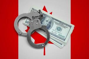 Canada flag  with handcuffs and a bundle of dollars. Currency corruption in the country. Financial crimes photo