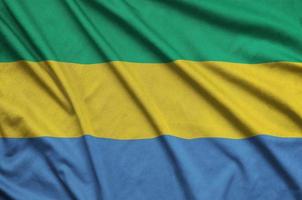 Gabon flag  is depicted on a sports cloth fabric with many folds. Sport team banner photo