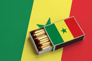 Senegal flag  is shown in an open matchbox, which is filled with matches and lies on a large flag photo