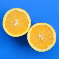 Top view of a several orange fruit slices on bright background in blue color. A saturated citrus texture image photo