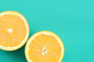 Top view of a several orange fruit slices on bright background in turquoise green color. A saturated citrus texture image photo