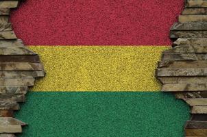 Bolivia flag depicted in paint colors on old stone wall closeup. Textured banner on rock wall background photo