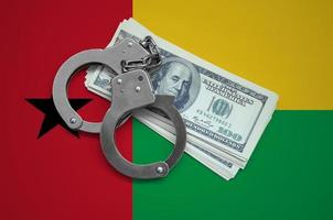 Guinea Bissau flag  with handcuffs and a bundle of dollars. Currency corruption in the country. Financial crimes photo