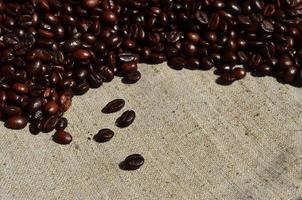 Texture of a gray canvas made of old and coarse burlap with coffee beans on it photo