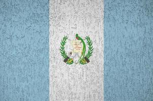 Guatemala flag depicted in bright paint colors on old relief plastering wall. Textured banner on rough background photo