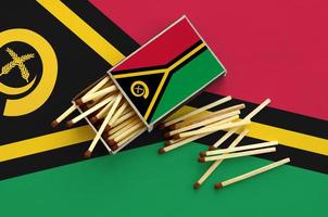 Vanuatu flag  is shown on an open matchbox, from which several matches fall and lies on a large flag photo