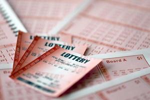 Red lottery ticket lies on pink gambling sheets with numbers for marking to play lottery. Lottery playing concept or gambling addiction. Close up photo