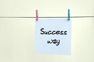 Success way. Note is written on a white sticker that hangs with a clothespin on a rope on a background of beige wall photo