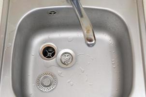 Silvery kitchen sink with a disassembled protective filter during the repair process photo