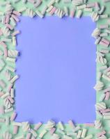 Colorful marshmallow laid out on green and lilac paper background photo