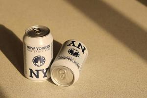 TERNOPIL, UKRAINE - JULY 18, 2022 Two cans of New Yorker fine lager beer with original logo and design on brown retro background photo