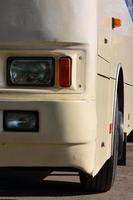 Photo of the hull of a large and long yellow bus. Close-up front view of a passenger vehicle for transportation and tourism