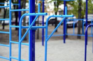 Sports bars in blue on the background of a street sports ground for training in athletics. Outdoor athletic gym equipment. Macro photo with selective focus and extremely blurred background