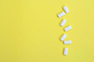 A few chewing gums lie on texture background of fashion pastel yellow color paper in minimal concept photo