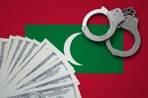 Maldives flag  with handcuffs and a bundle of dollars. The concept of illegal banking operations in US currency photo