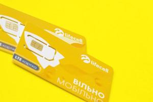 TERNOPIL, UKRAINE - JULY 5, 2022 Lifecell new sim card with free contract on yellow background. Lifecell is ukrainian mobile telephone network operator and provider of wireless connection photo