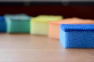 A few kitchen sponges lie on a wooden kitchen countertop. Colorful objects for washing dishes and cleaning in the house are ready for use photo