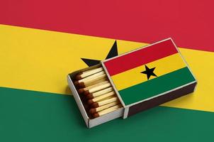 Ghana flag  is shown in an open matchbox, which is filled with matches and lies on a large flag photo