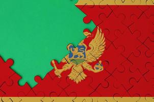 Montenegro flag  is depicted on a completed jigsaw puzzle with free green copy space on the left side photo