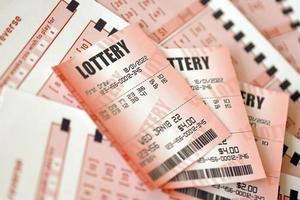 el billete de lotería rojo se encuentra en hojas de juego rosas con números para marcar para jugar a la lotería. concepto de juego de lotería o adicción al juego. de cerca foto