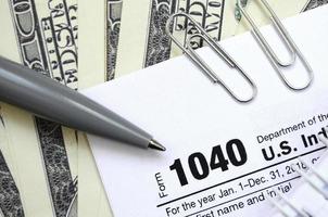 el bolígrafo, el cuaderno y los billetes de dólar se encuentran en el formulario de impuestos 1040 de la declaración de impuestos sobre la renta de las personas físicas. la hora de pagar impuestos foto