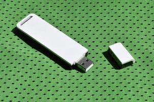 A modern portable USB wi-fi adapter is placed on the green sportswear made of polyester nylon fiber photo