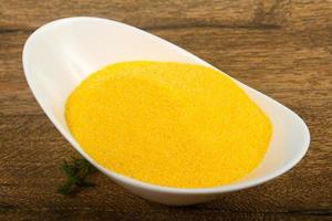 Raw polenta in a bowl on wooden background photo