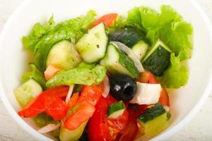 Greek salad in a bowl on wooden background photo