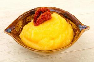 Polenta in a bowl on wooden background photo