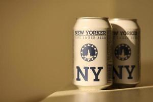TERNOPIL, UKRAINE - JULY 18, 2022 Two cans of New Yorker fine lager beer with original logo and design on brown retro background photo