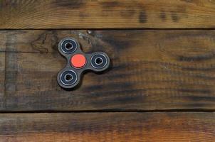 A rare handmade wooden fidget spinner lies on a brown wooden background surface. Trendy stress relieving toy photo