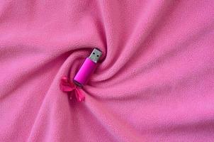 Brilliant pink usb flash memory card with a pink bow lies on a blanket of soft and furry light pink fleece fabric with a lot of relief folds. Memory storage device in women's design photo