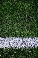 White stripe on a bright green artificial grass soccer field photo