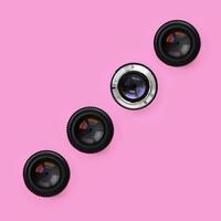 A few camera lenses with a closed aperture lie on texture background of fashion pastel pink color paper in minimal concept. Abstract trendy pattern photo