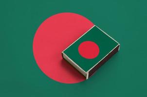 Bangladesh flag  is pictured on a matchbox that lies on a large flag photo